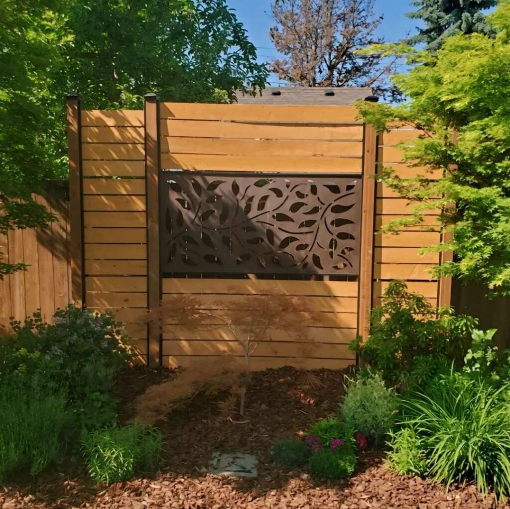 Wooden fence with decorative metal panel insert