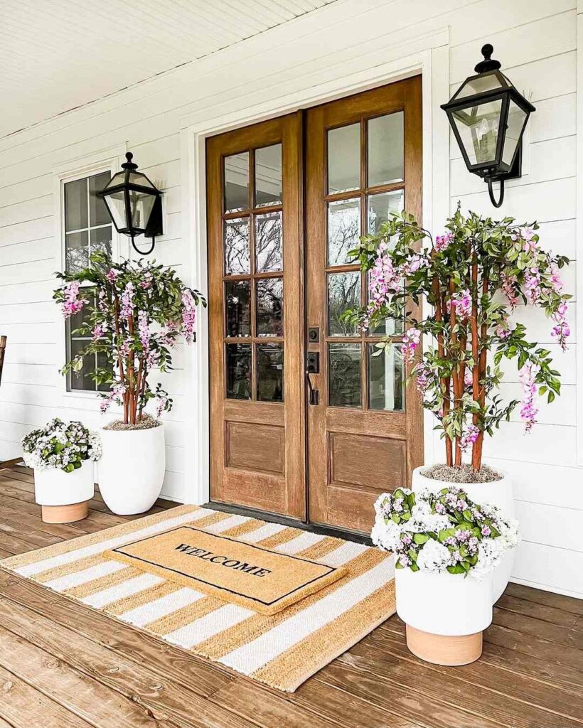 Wooden doors with flowering plants and welcome mat