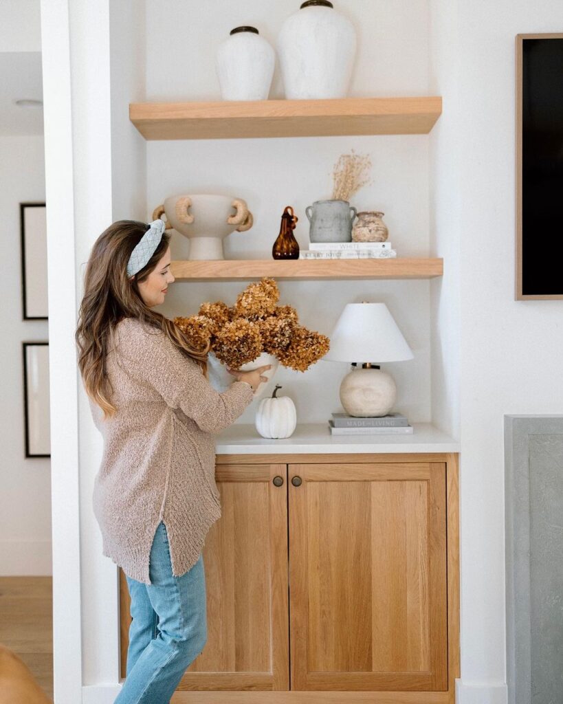 Woman arranging fall decor on shelves