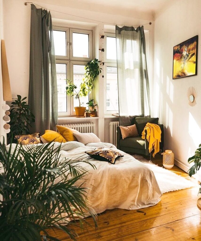 Cozy bedroom with plants, natural light, and warm colors.