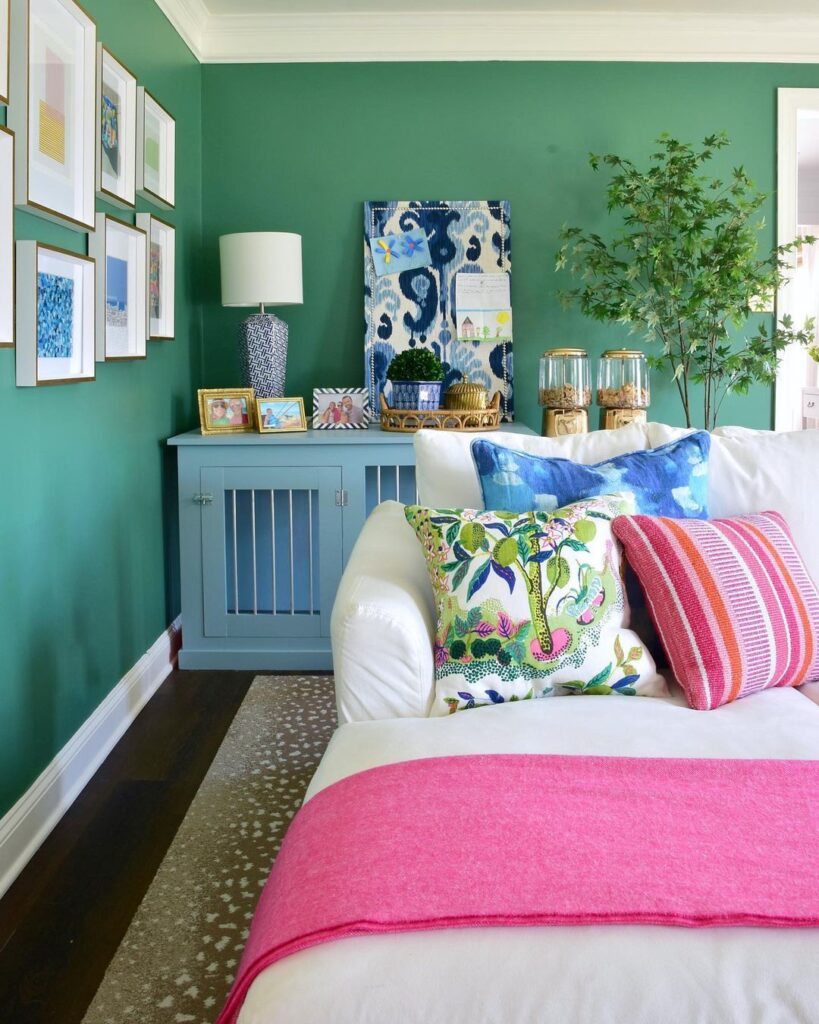 Green bedroom with colorful pillows, artwork