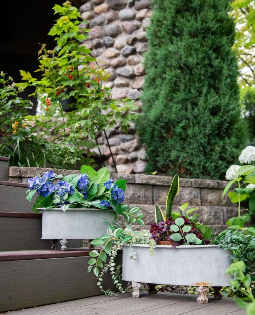 White planters on steps with colorful flowers