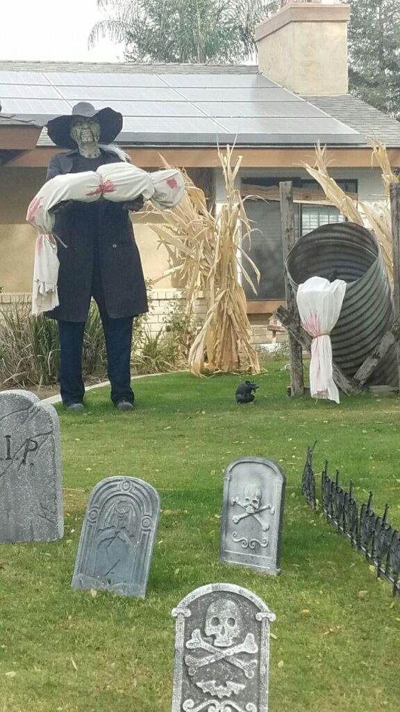 Creepy figure holding bundle in makeshift graveyard