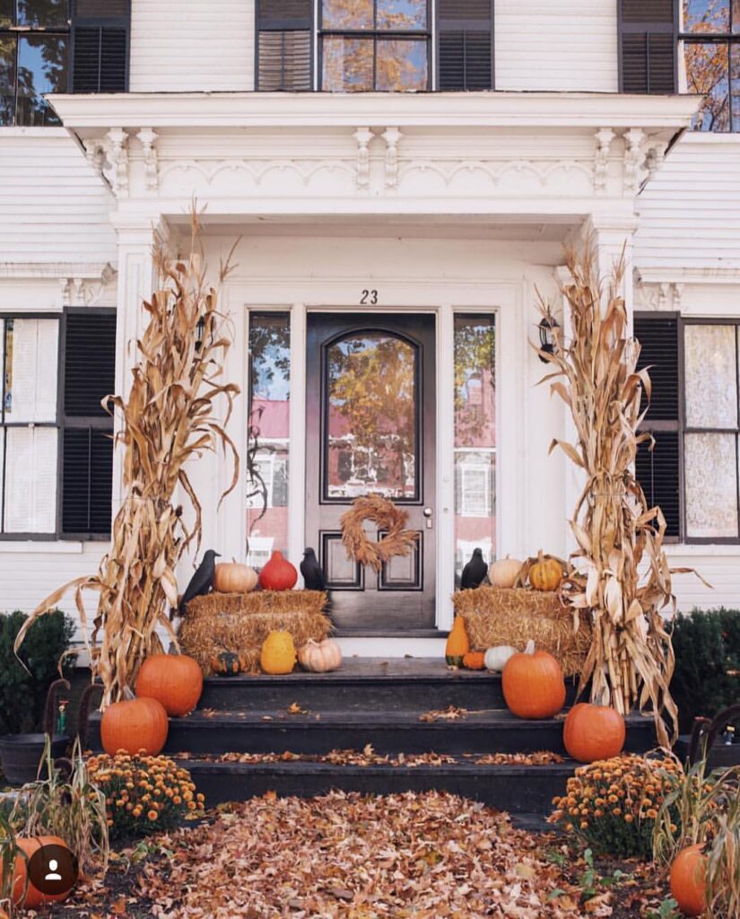 White porch, cornstalks, pumpkins, hay bales