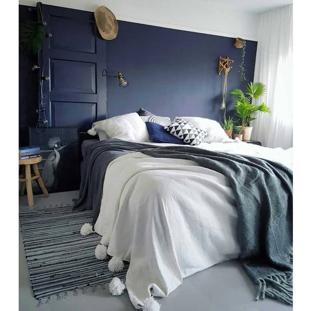 Bedroom with navy wall, white bedding, plants