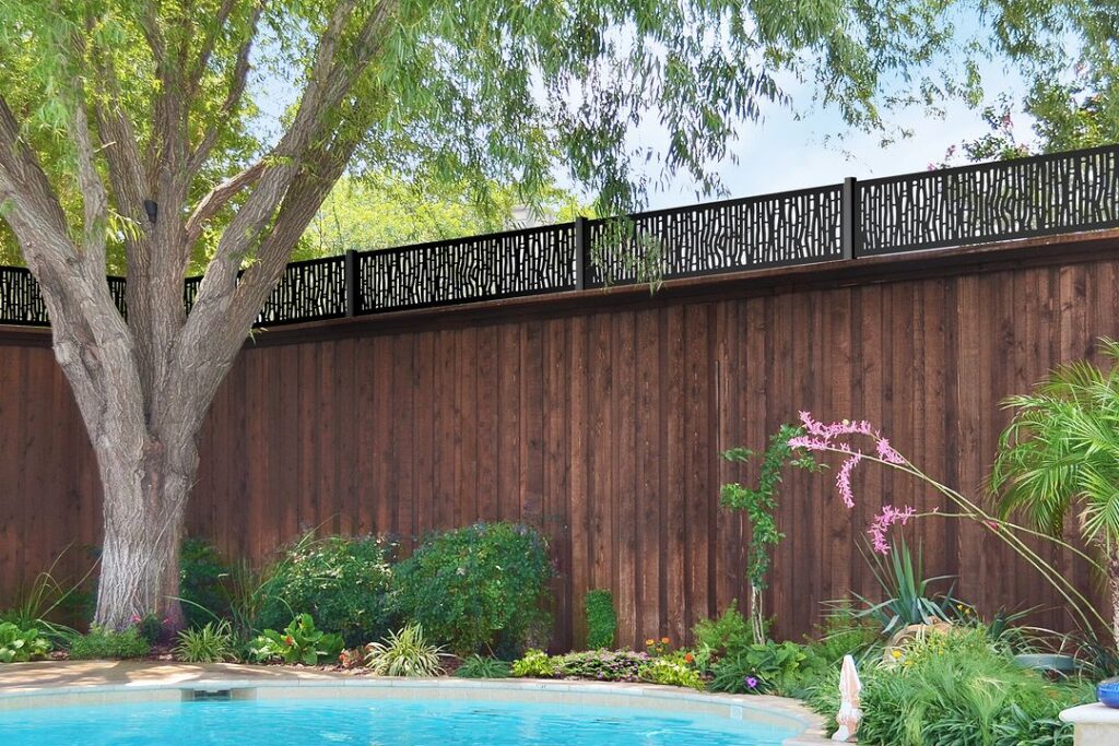 Wooden fence with metal top near pool and garden