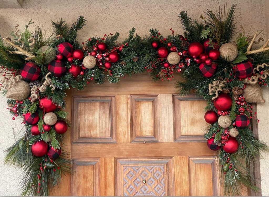 Evergreen garland with red ornaments framing door