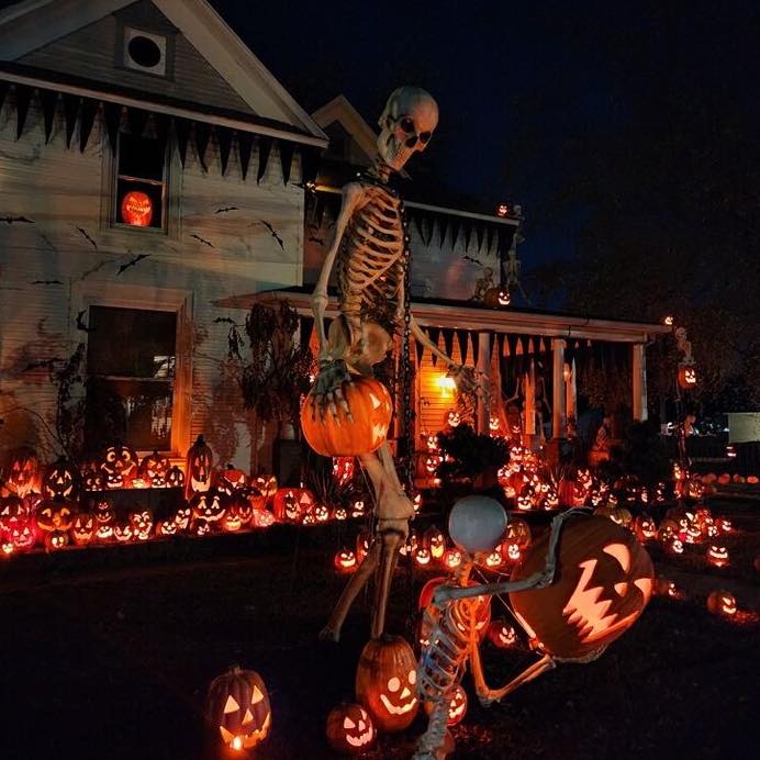 Giant skeleton with glowing pumpkins at night