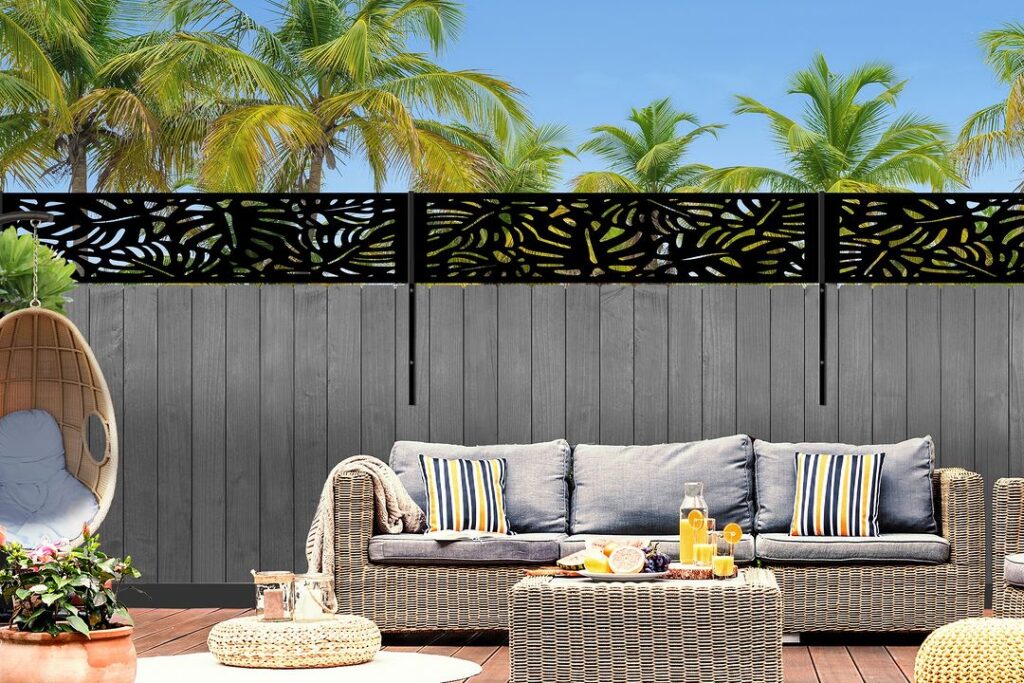 Gray fence with decorative top near outdoor furniture