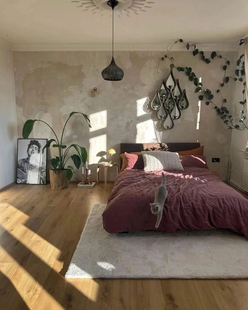 Bohemian bedroom with burgundy bedding, plants, and vintage-inspired decor.