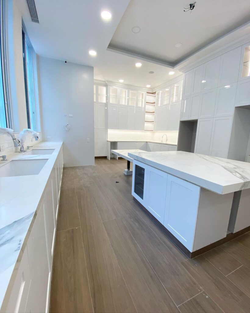 Bright white kitchen with marble island and wood floors