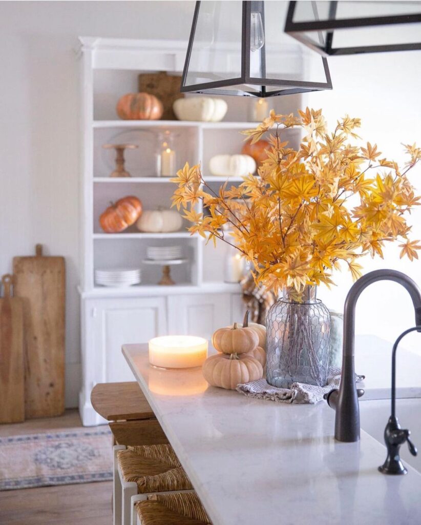 Autumn kitchen island with leaves, pumpkins, and candle.