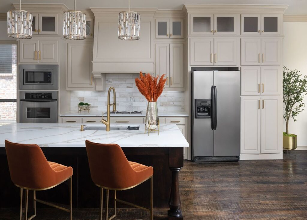 Elegant kitchen with white cabinets and orange accents.