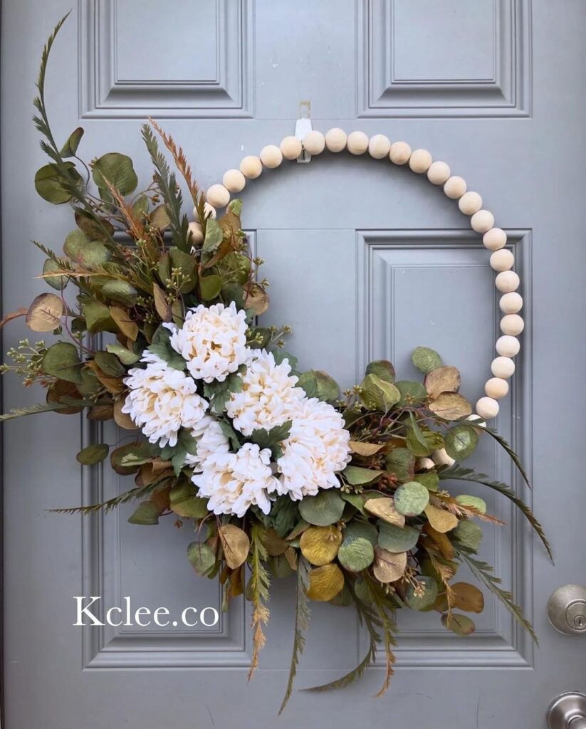 Elegant fall wreath featuring wooden beads and white flowers on gray door