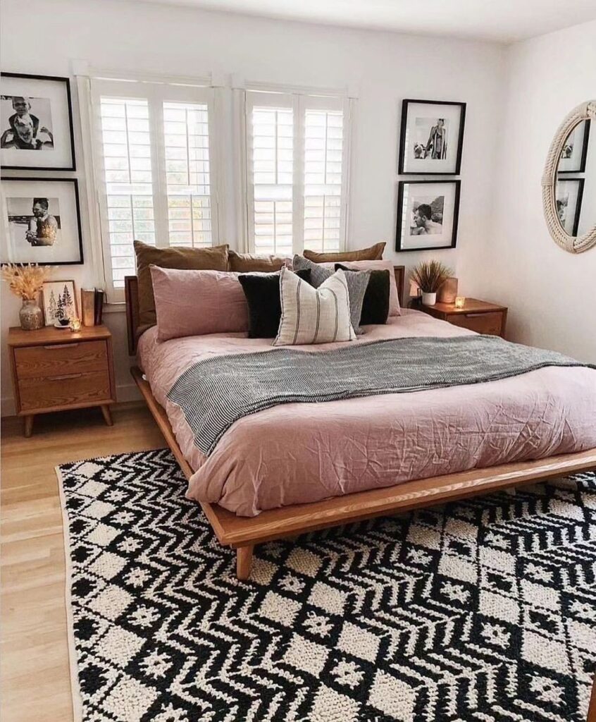 Bedroom with pink bedding wooden frame and black and white rug

