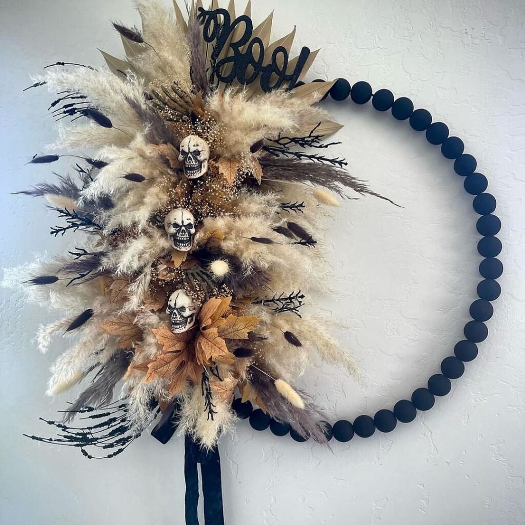 Boho Halloween hoop wreath with feathers skulls and BOO sign.