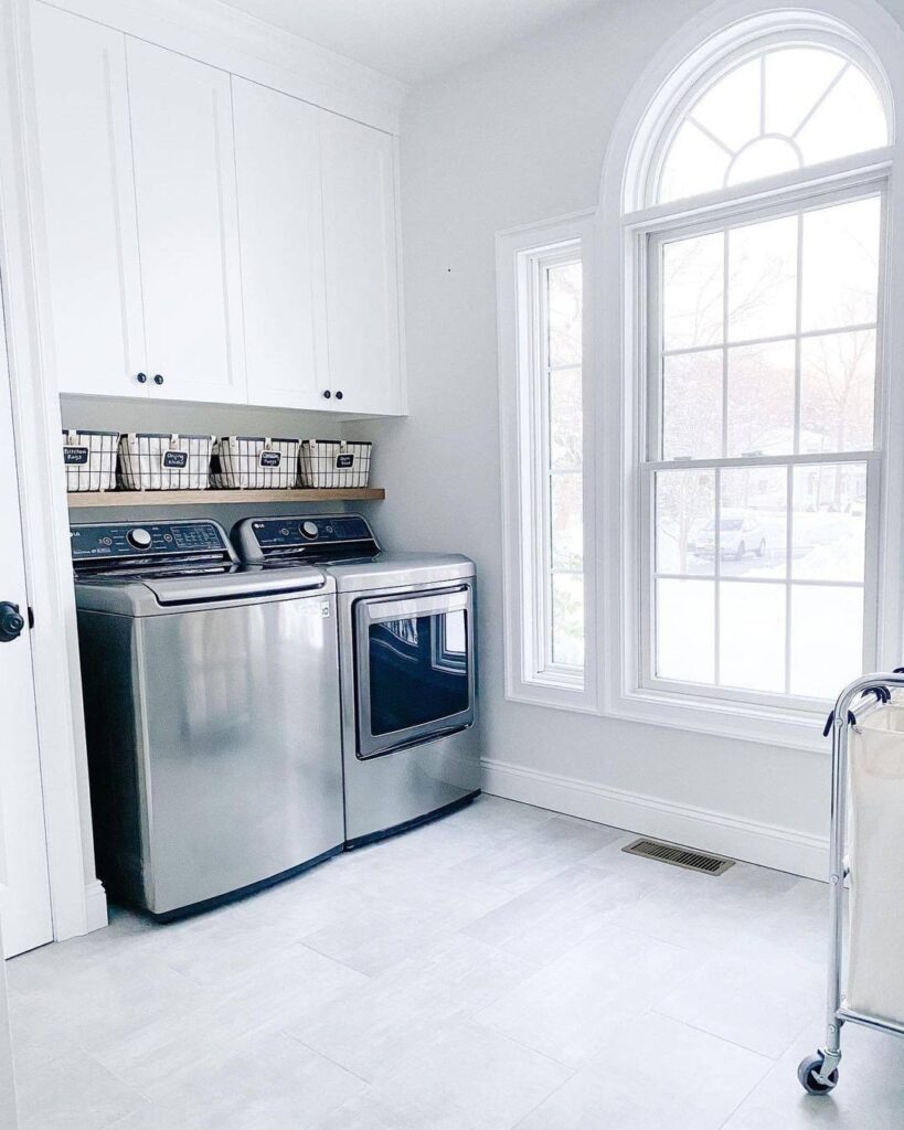 Bright white laundry room with top-load machines and arched window.