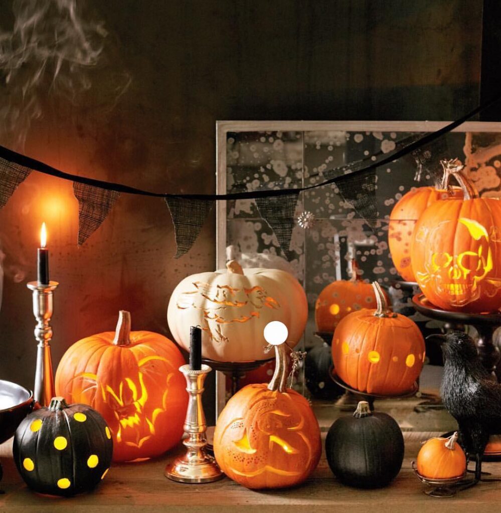 Carved pumpkins illuminated by candlelight on dark table