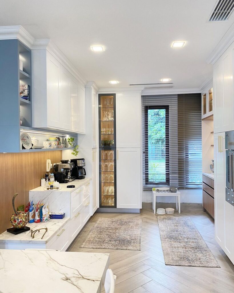 White kitchen with blue shelves and tall glass cabinet.