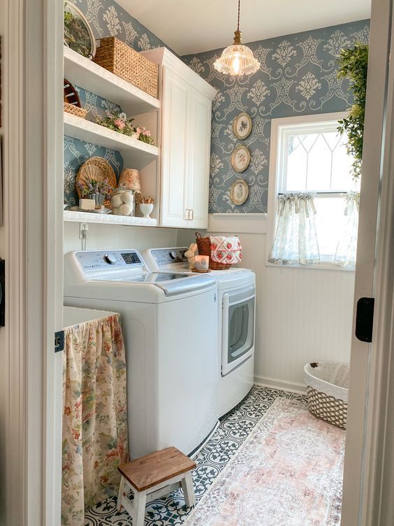 Cozy laundry room with floral wallpaper, open shelving, and patterned floor tiles.