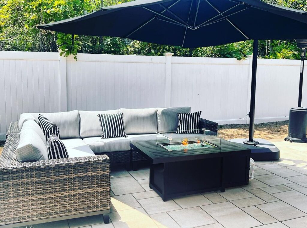 Gray wicker patio set with black fire table and navy umbrella