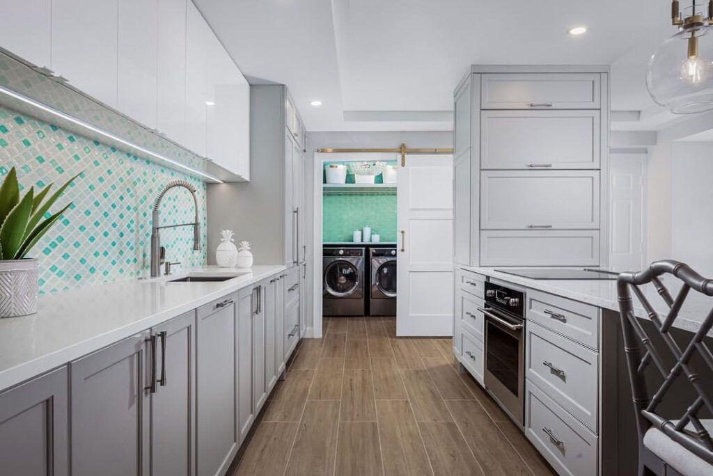 Kitchen leading to laundry room with green tile backsplash