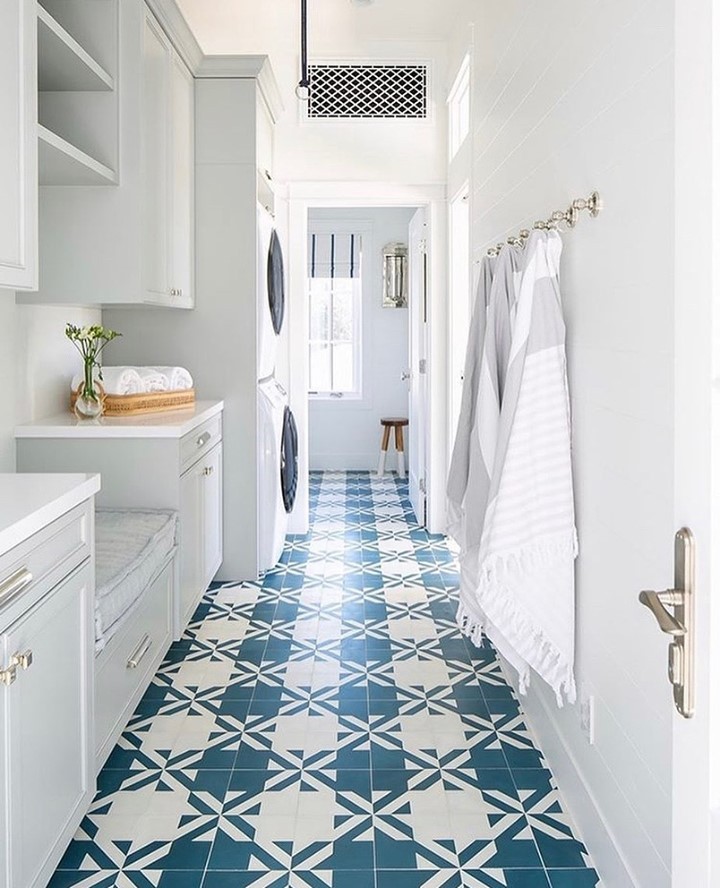 Bright laundry hallway with blue-white geometric floor tiles and white cabinets.