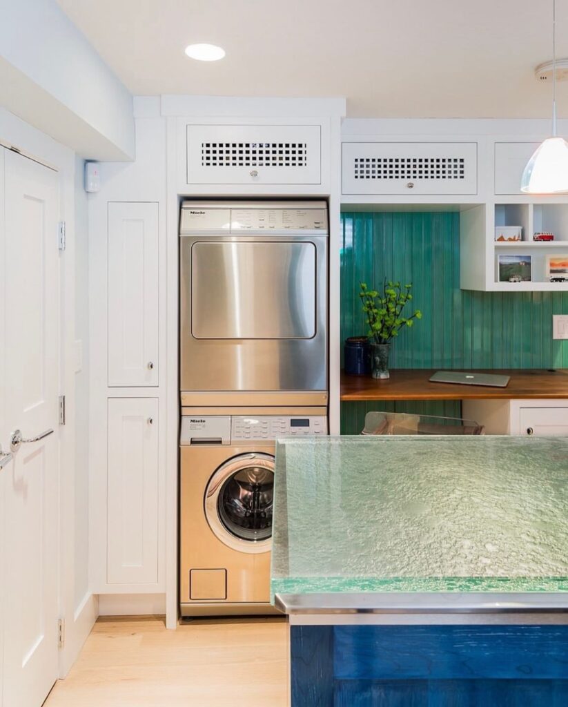 White laundry nook with stacked machines and teal beadboard accent