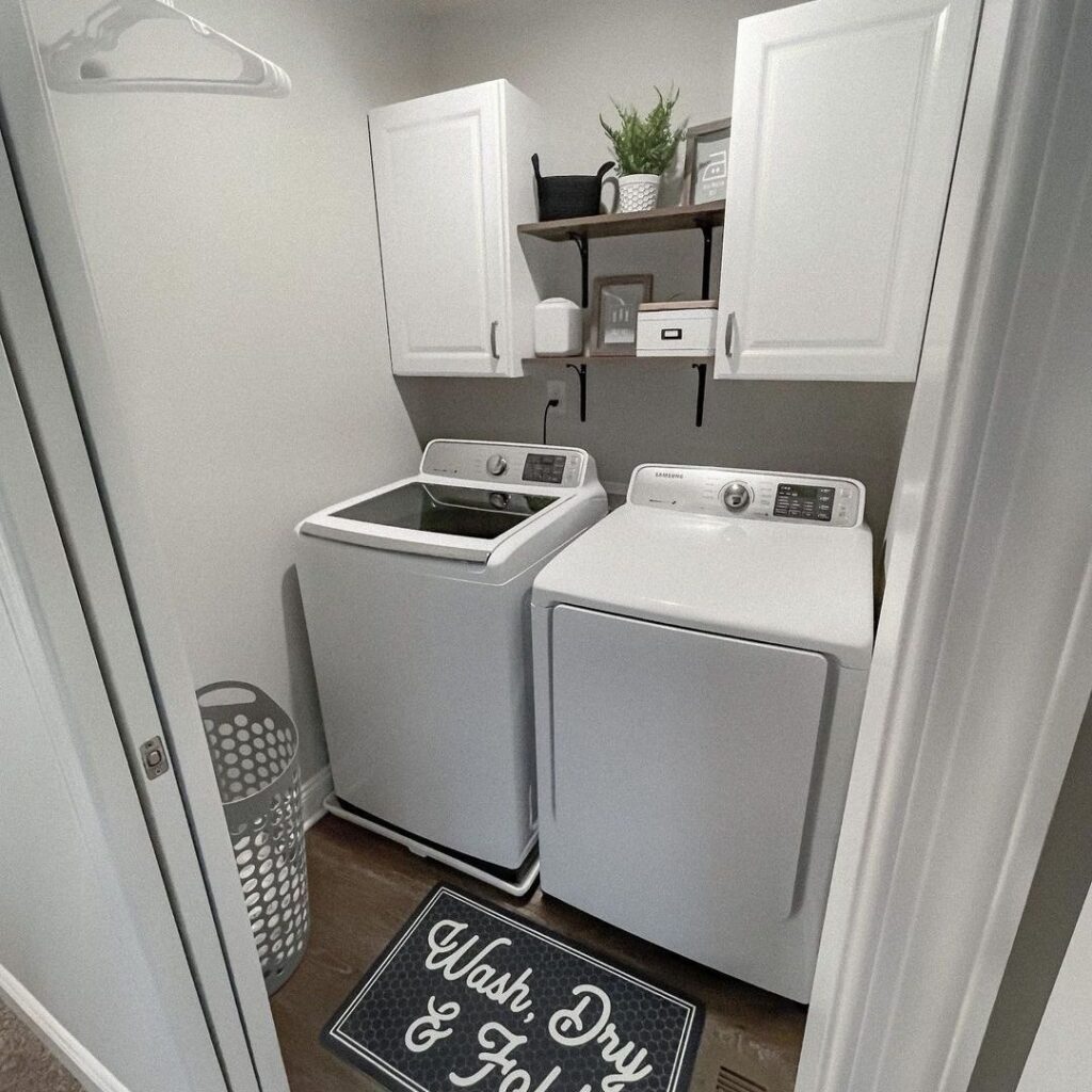 Small laundry closet with white cabinets shelves and decorative mat