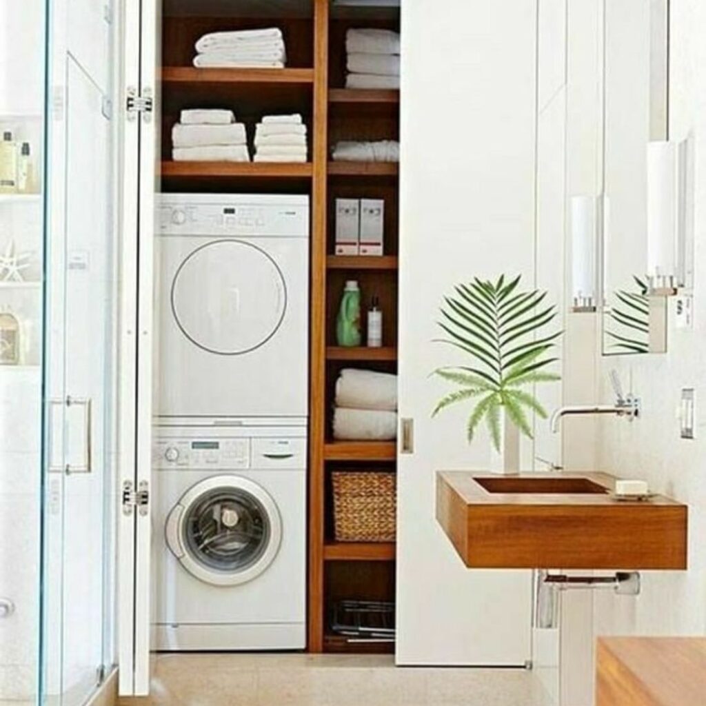 Compact laundry closet with stacked machines, shelving.