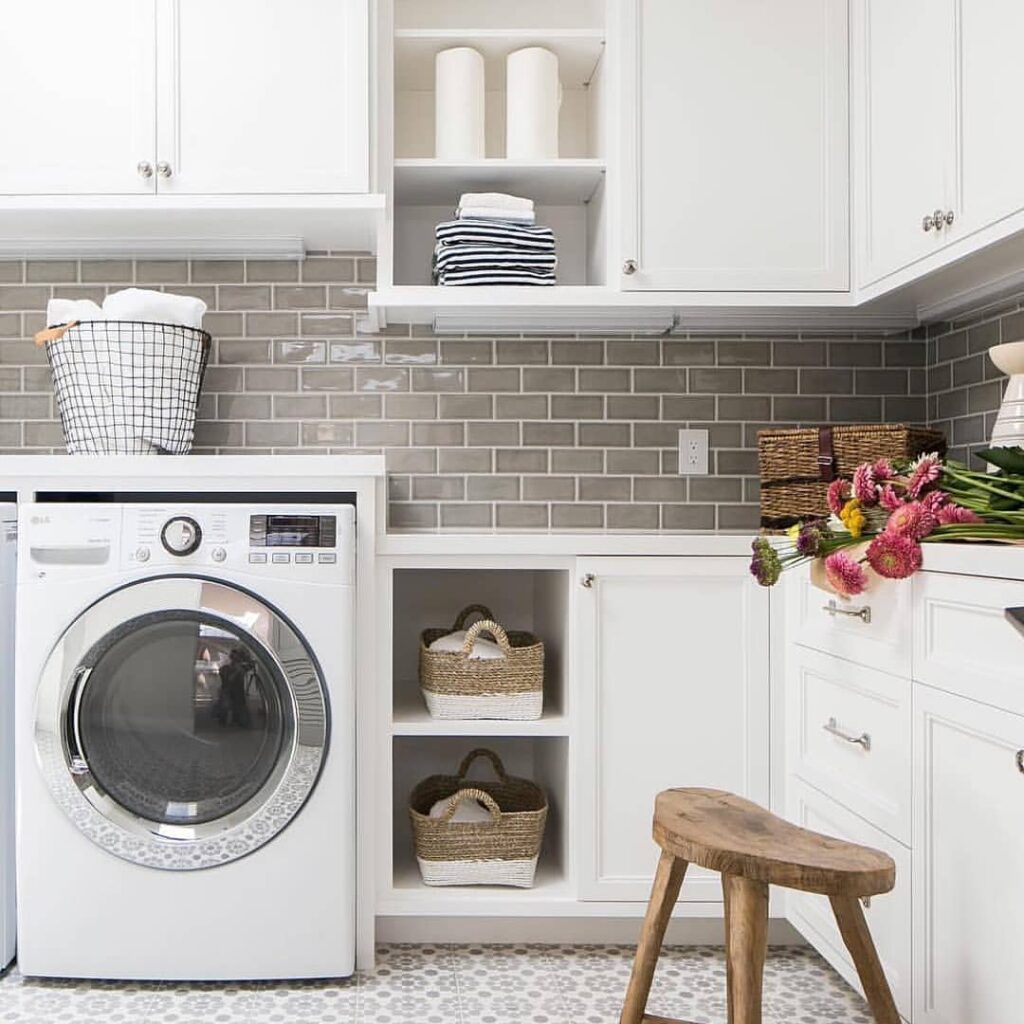 Bright laundry room with white cabinets and flower bouquet.