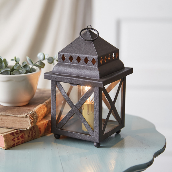 Metal lantern with candle books and plant on blue table