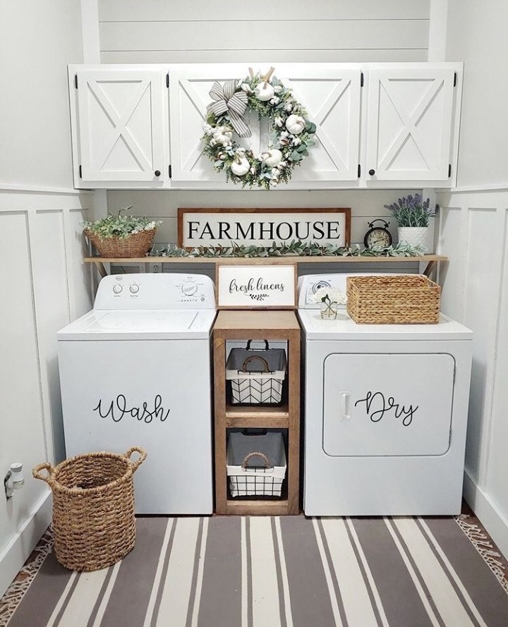 Farmhouse laundry room with white top-load washer dryer and decorative wreath.