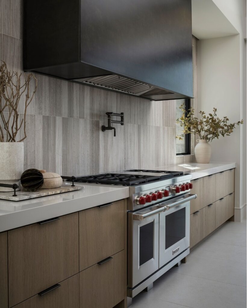 Luxury beige kitchen with wood cabinets gray backsplash and professional range.