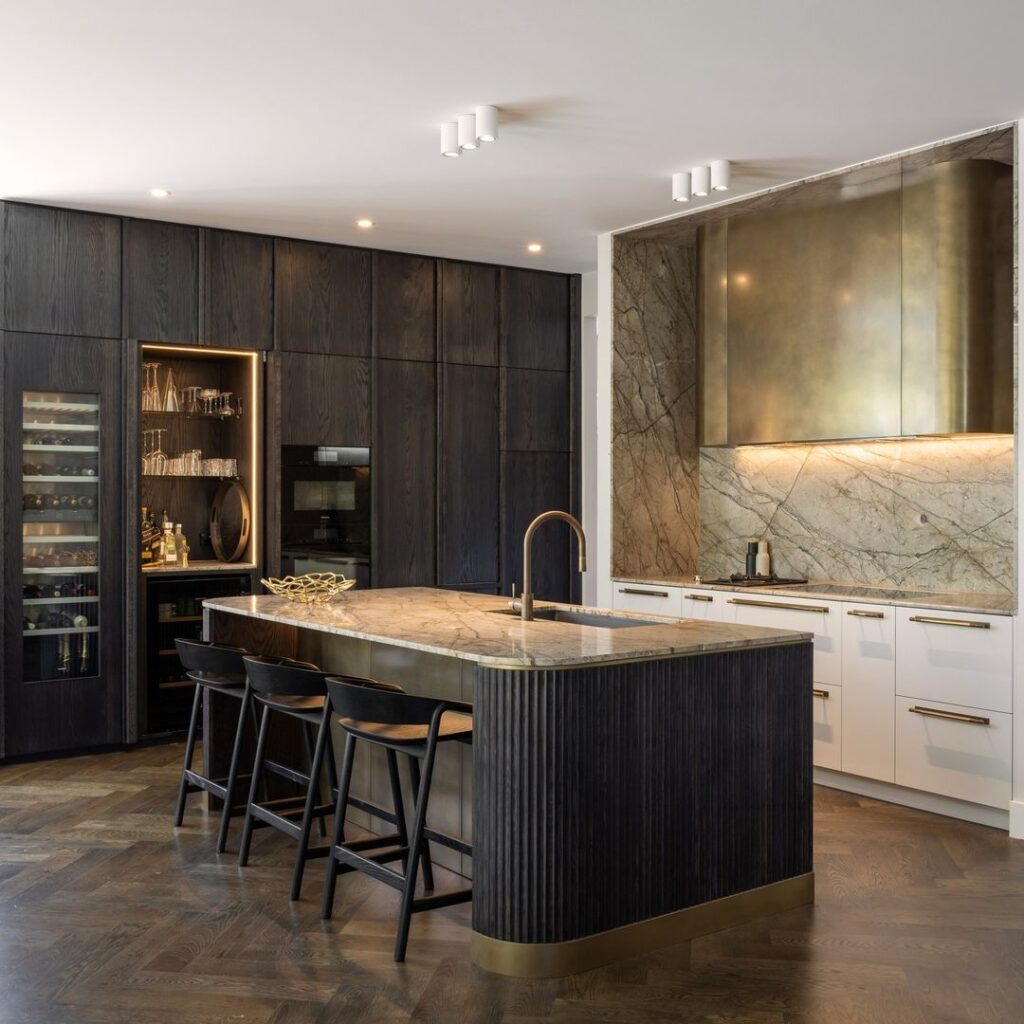 Elegant kitchen with dark cabinets marble island and gold details.