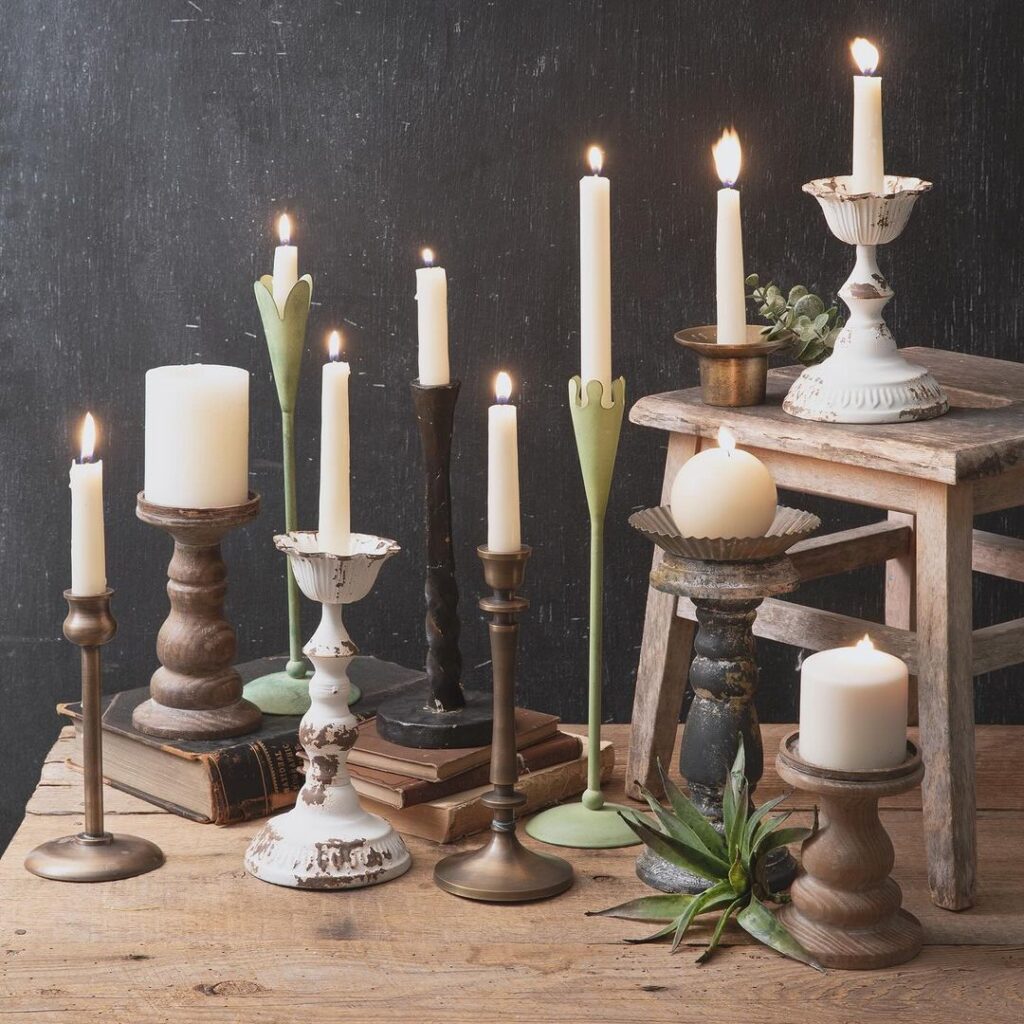 Assorted candle holders with lit candles on wooden surface