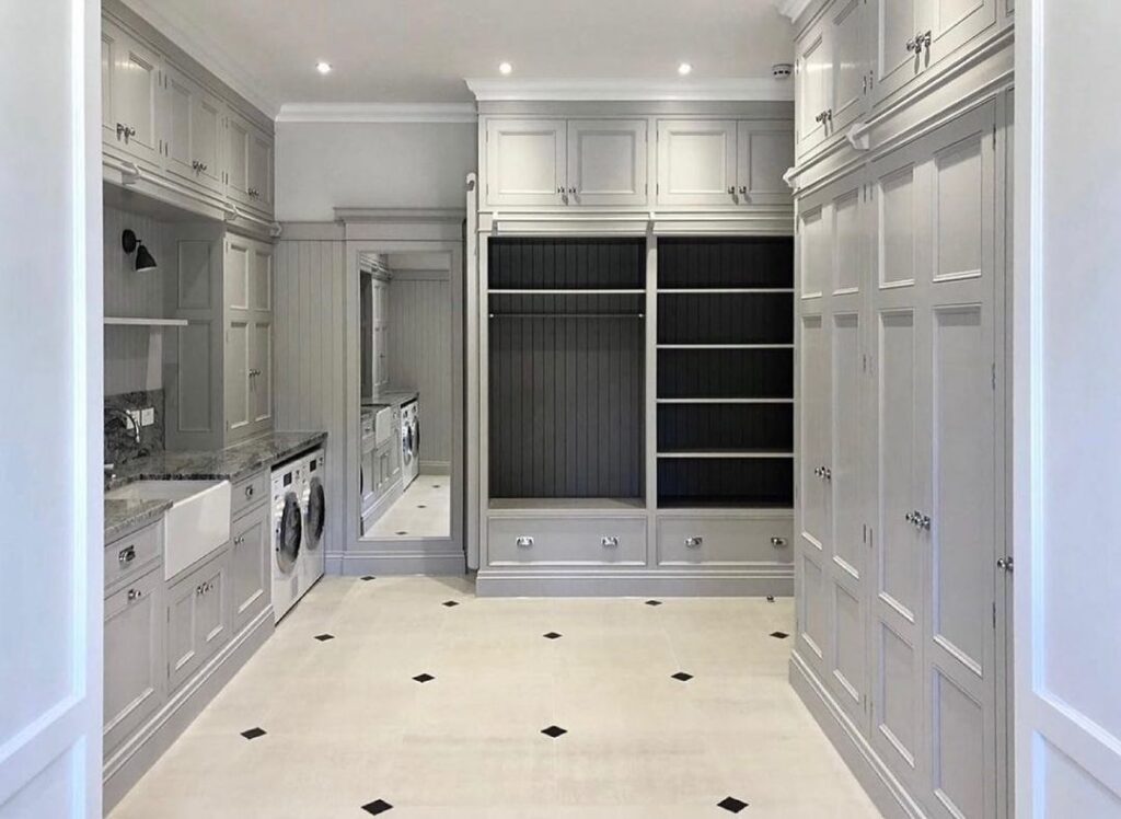 Luxurious gray laundry room with built-in cabinets and tiled floor