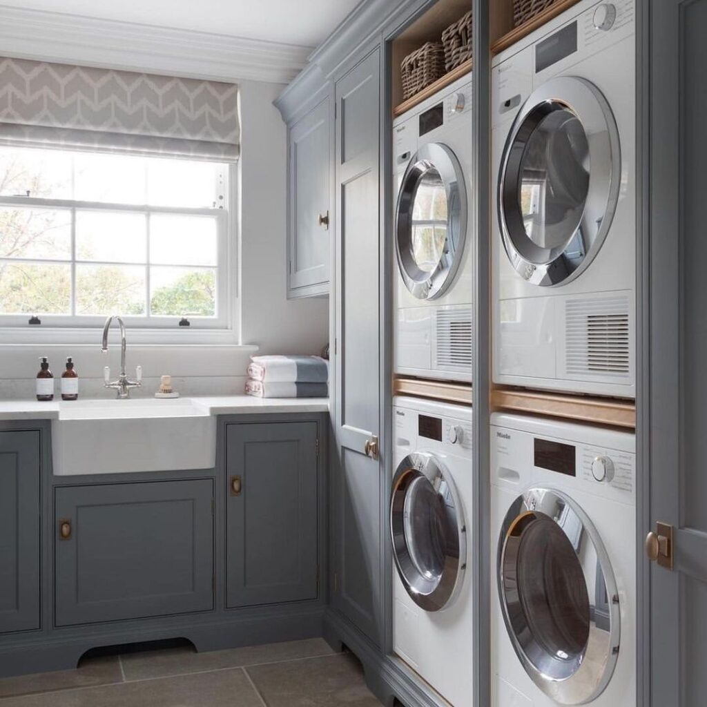 Upscale laundry room with gray cabinets and stacked white appliances.