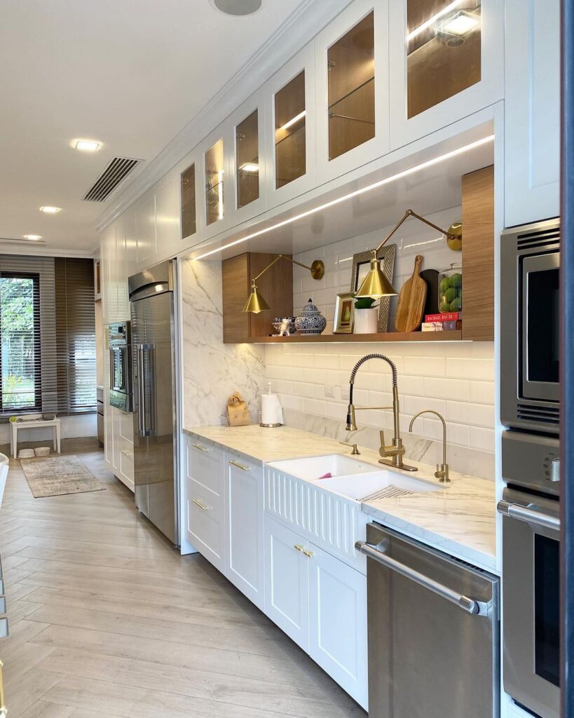 White kitchen with glass cabinets and brass fixtures.