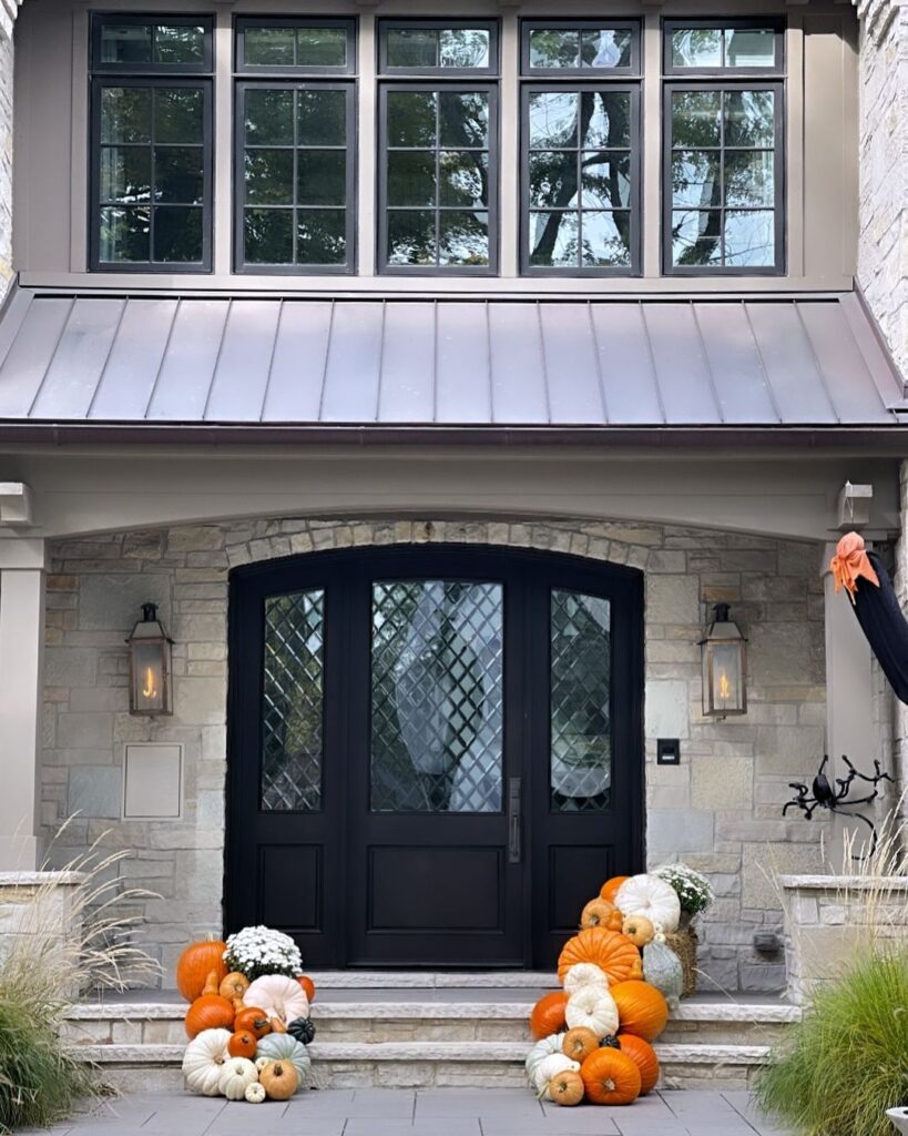 Stone entryway with black door and colorful pumpkin display