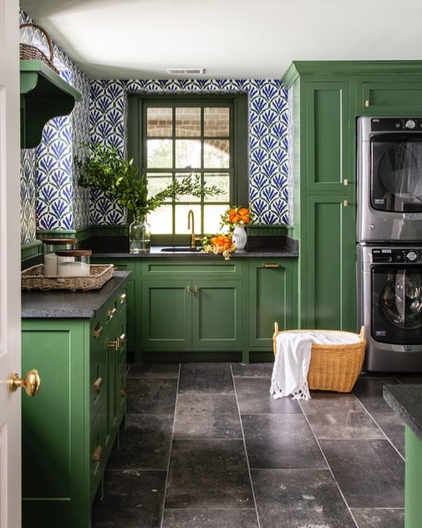 Green laundry room with blue patterned wallpaper and dark floor.