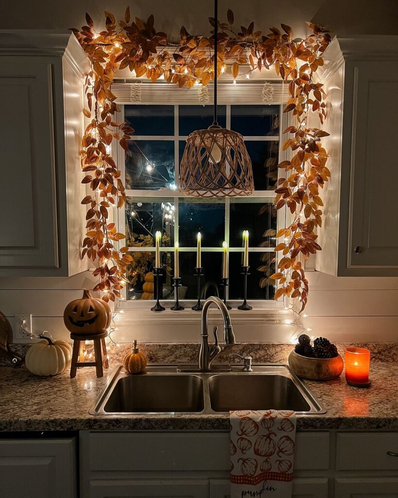 Kitchen window decorated with autumn leaves lights and pumpkins