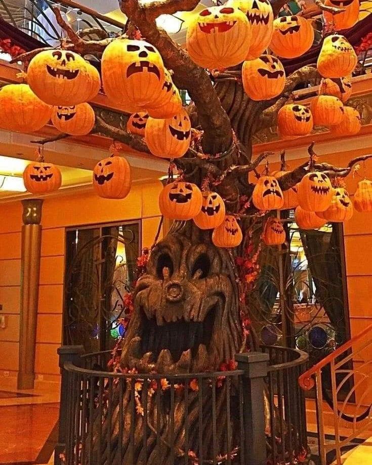 Illuminated pumpkin-laden tree with spooky face.