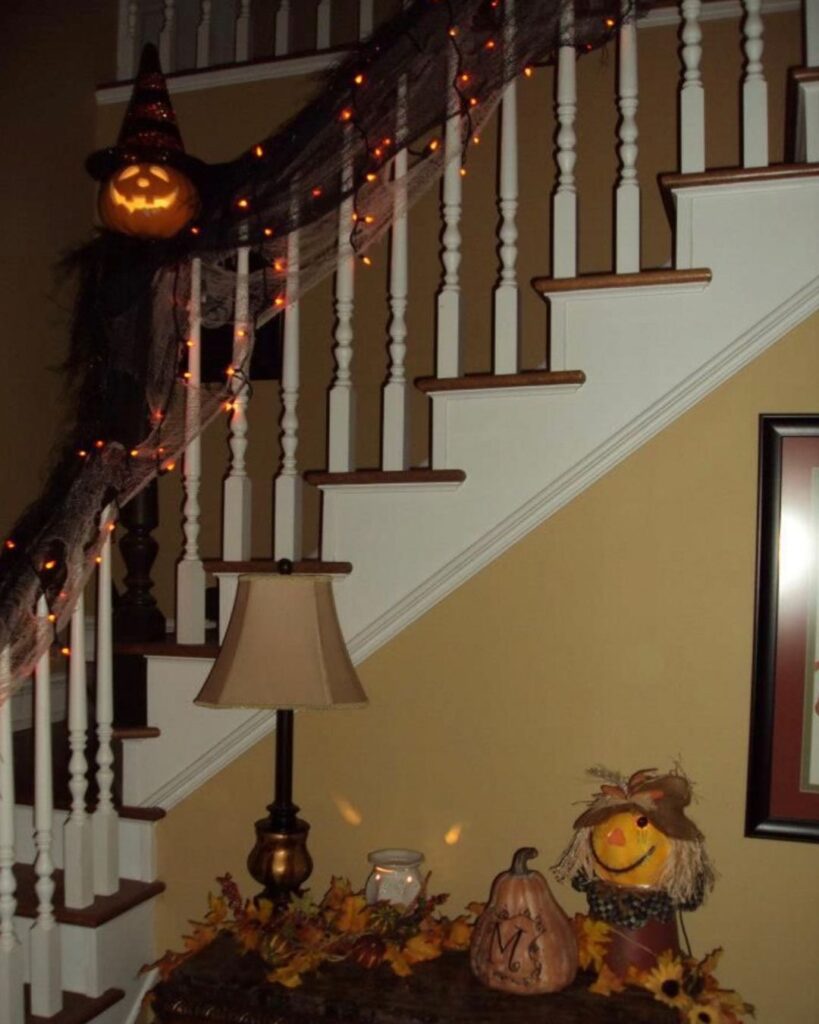 Halloween-decorated staircase with lights and fall decorations.