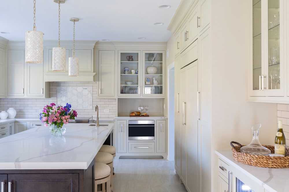 Bright white kitchen with glass pendant lights and colorful flowers.