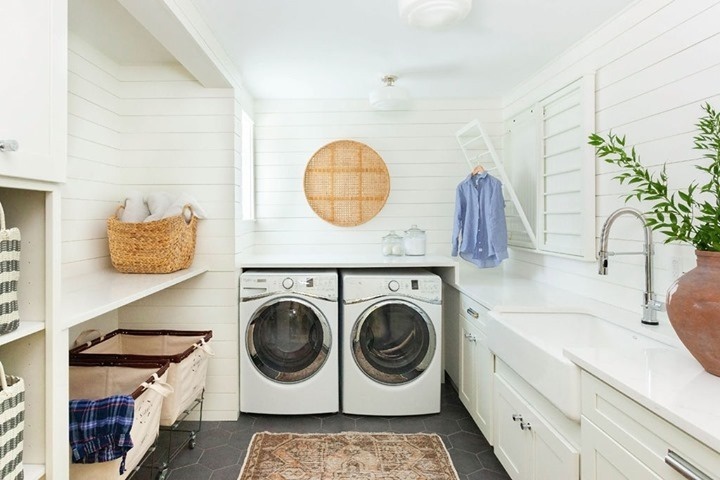 White coastal laundry room with modern appliances woven decor and plants.