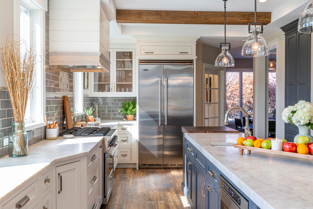 Modern farmhouse kitchen with white and navy cabinets and wooden beam.