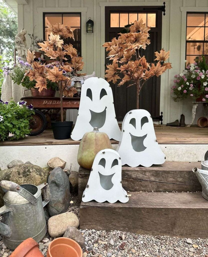 Smiling ghost cutouts and autumn plants on farmhouse porch