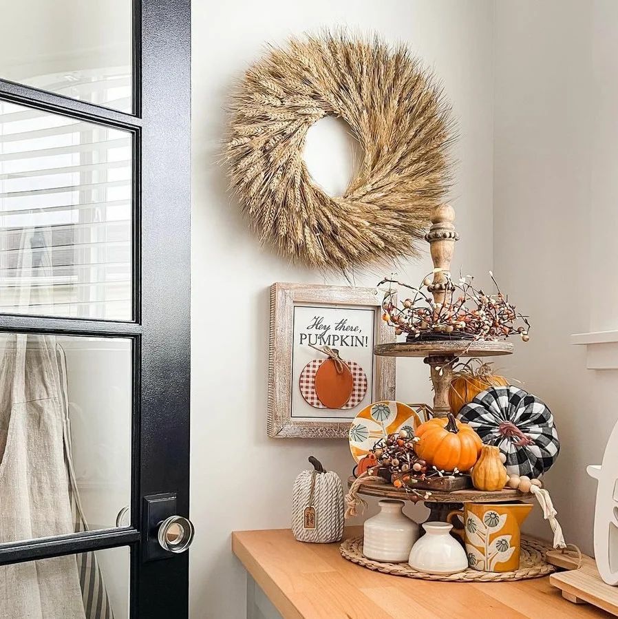 Wheat wreath above fall decor with pumpkins and signs