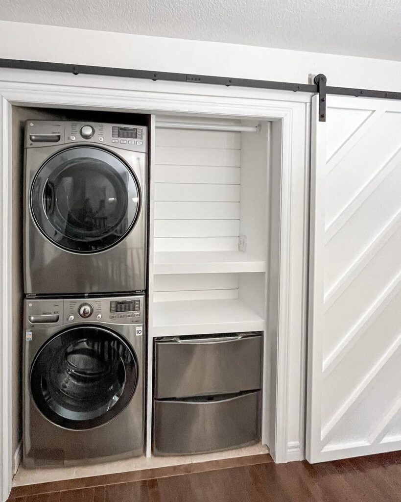 Laundry closet with stacked washer dryer behind sliding barn door